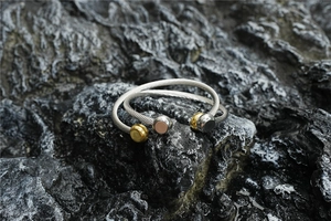 Détail de la texture torsadée et des embouts sphériques sur bracelets ouverts en acier