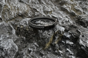 Nahaufnahme eines schwarzen Lederarmbands mit Magnetverschluss auf grauem Steinuntergrund