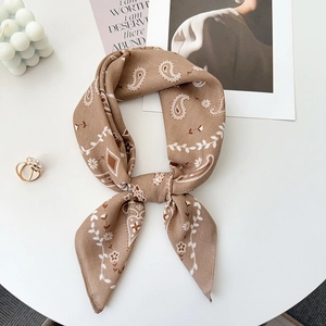 Detail of a brown paisley silk scarf with satin finish on white background