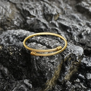 Bracelet jonc doré en acier titane avec motif torsadé sur un fond en pierre naturelle