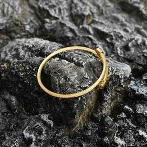 Bracelet torsadé en acier titane avec finition dorée et embouts cylindriques élégants