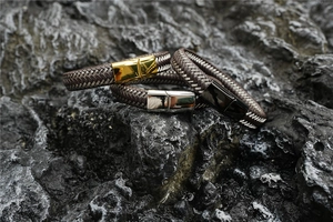 Braided leather bracelets for men with gold, silver, and black metal clasps on rock