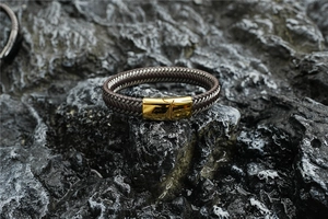 Detailed close-up of woven leather bracelet texture with polished gold metal buckle