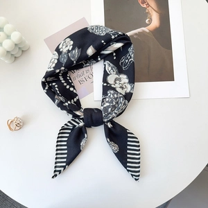 Detailed view of luxury silk scarf with herringbone and floral print on white table