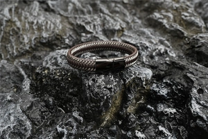 Macro shot of men's braided leather bracelet with glossy black magnetic clasp on rock