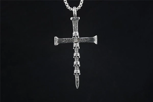 Macro shot of gothic cross necklace with stacked skulls and Deathly engraving