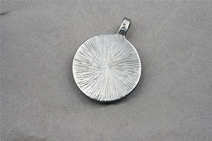 Detailed macro view of silver warrior pendant back with radial texture and chevron bail