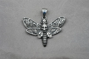 Détail d'un pendentif papillon en acier titane oxydé vintage avec crâne central précis
