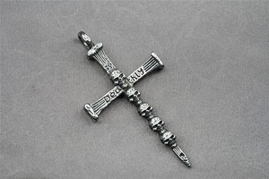 Macro detail of gothic cross pendant with five skulls and engraved silver textures