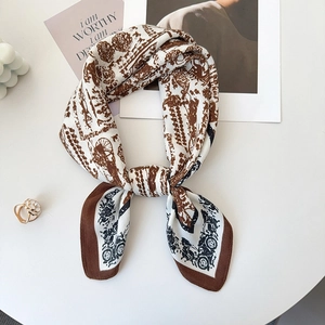 Close-up of vintage carriage pattern silk scarf with elegant brown contrast hem on white