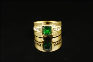 Macro shot of men's gold titanium ring featuring a square green gemstone and side diamonds