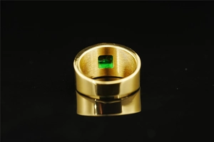 Macro shot of gold ring showing brushed metal inner texture and green gemstone inlay