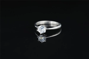 Macro shot of a minimalist silver titanium ring featuring a six-prong set moissanite stone