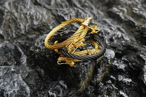 Macro shot of titanium steel dragon heads on woven cable bracelets over volcanic rock