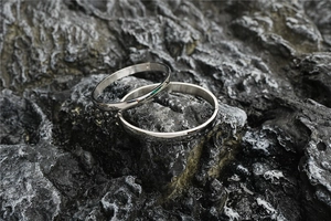Close-up of minimalist silver titanium steel bangles on dark natural rock background