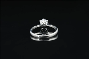 Macro side view of round moissanite in classic six-prong setting on polished steel band