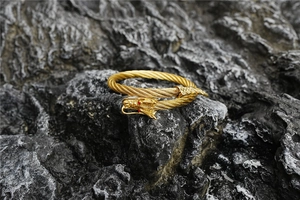 Detailed view of vintage gold dragon head bracelet with red eyes on textured stone