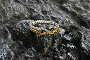 Detailed view of gold and silver Viking lion head bracelets on a natural rock background