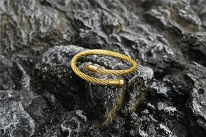 Macro shot of gold wire cable nail bracelet with industrial textured rock background