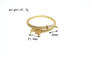 Detailed close-up of golden dragon bangle with red gemstone eyes and cable wire texture