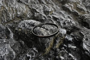 Detail of matte black brushed finish titanium steel cuff bracelet on dark stone background