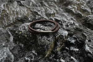 Detail of hand-woven brown and black leather bracelet with brushed metal magnetic clasp