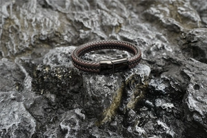 Gros plan du bracelet en cuir tressé sur roche volcanique avec fermoir magnétique noir