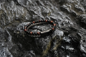 Detailed close-up of tiger eye stone beads and braided leather rope on volcanic rock