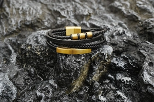 Detail of multi-layer leather braided bracelet with gold magnetic clasp on dark rock