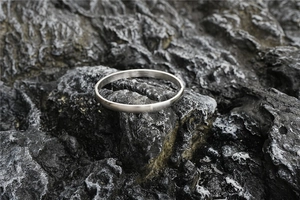 Macro shot of silver titanium steel bangle with brushed texture on black stone