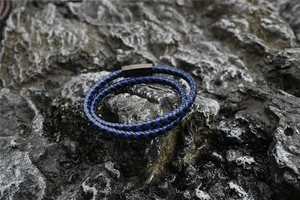 Detailed macro of a double-layered black and blue braided cord bracelet with matte metal clasp