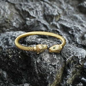 Golden twisted cable bracelet with double leopard heads and green gemstone eyes