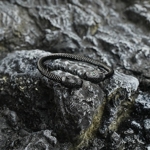 Black twisted steel bracelet featuring two leopard heads with emerald green eyes detail