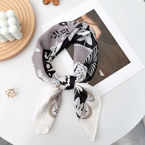 Elegant black and white floral silk scarf styled as a neckerchief on a white table