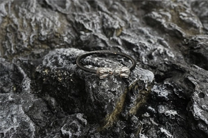 Détail macro du bracelet ouvert tête de loup viking avec câble noir sur roche sombre
