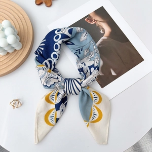 Blue and yellow floral silk scarf tied in a bow on a wooden tray with candle