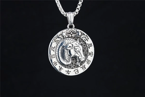 Macro detail of zodiac goat pendant with engraved Chinese characters on a box chain