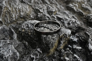 Detail of matte black brushed stainless steel bracelet on dark volcanic rock
