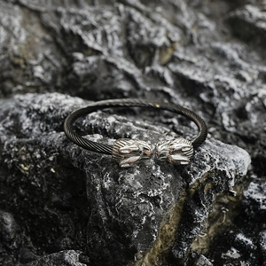 Bracelet torque torsadé tête de loup en acier inoxydable noir sur une roche sombre