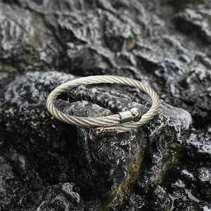 Sleek stainless steel braided cable open bangle with polished ball ends on rock