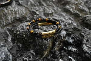 Détail de perles en œil de tigre et bracelet en cuir avec fermoir magnétique doré poli