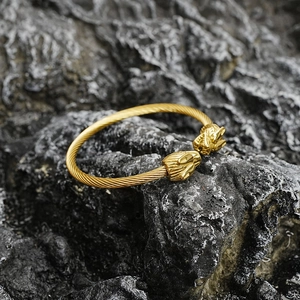 Bracelet jonc Viking doré avec tête de loup et câble torsadé sur fond de pierre grise