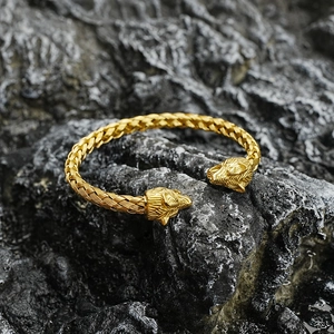 Golden titanium steel braided wolf head cuff bracelet shown on dark rock background