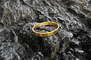 Close-up of golden stainless steel bracelet with brushed texture on black rock surface