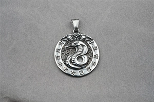 Macro detail of retro zodiac pendant featuring a carved snake and Chinese characters