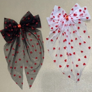 Detail of sheer mesh bow hair clips with red flocked heart patterns and satin ribbons