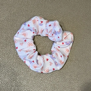 Detail of white scrunchie with red hearts and rainbow prints on soft fabric