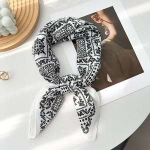 Gros plan d'un foulard en soie à motif paisley noir et blanc noué sur un bureau