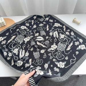 Macro detail of silk scarf featuring camellia and pearl prints with striped borders