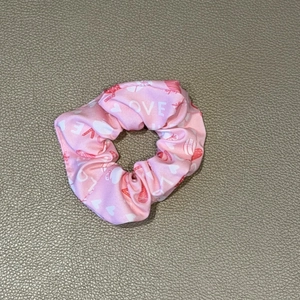 Detailed view of a pink scrunchie with white LOVE text and red heart pattern print